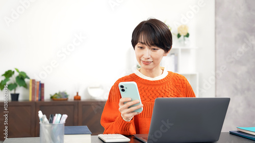 スマホとノートパソコンを使うミドル女性
