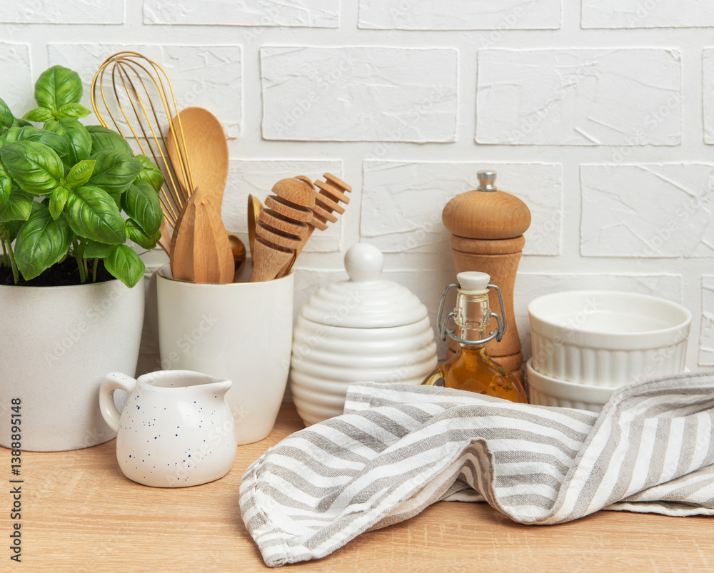 Kitchen utensils, basil plant and linen napkin creating cozy atmosphere on table