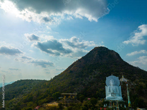 A majestic large sitting Buddha statue meditating amidst lush green hills and natural light. This peaceful place showcases the harmony of sacred architecture and natural beauty. mountain background