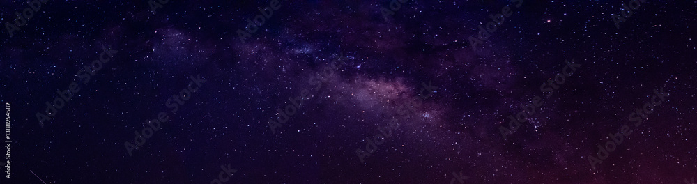Fototapeta premium Milky way in night sky and stars on dark background with noise and grain. Long exposure and white balance. Panoramic photo. 