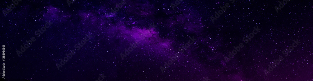 Naklejka premium Milky way in night sky and stars on dark background with noise and grain. Long exposure and white balance. Panoramic photo. 