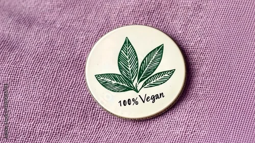 100 percent vegan badge with leaf design on purple fabric background