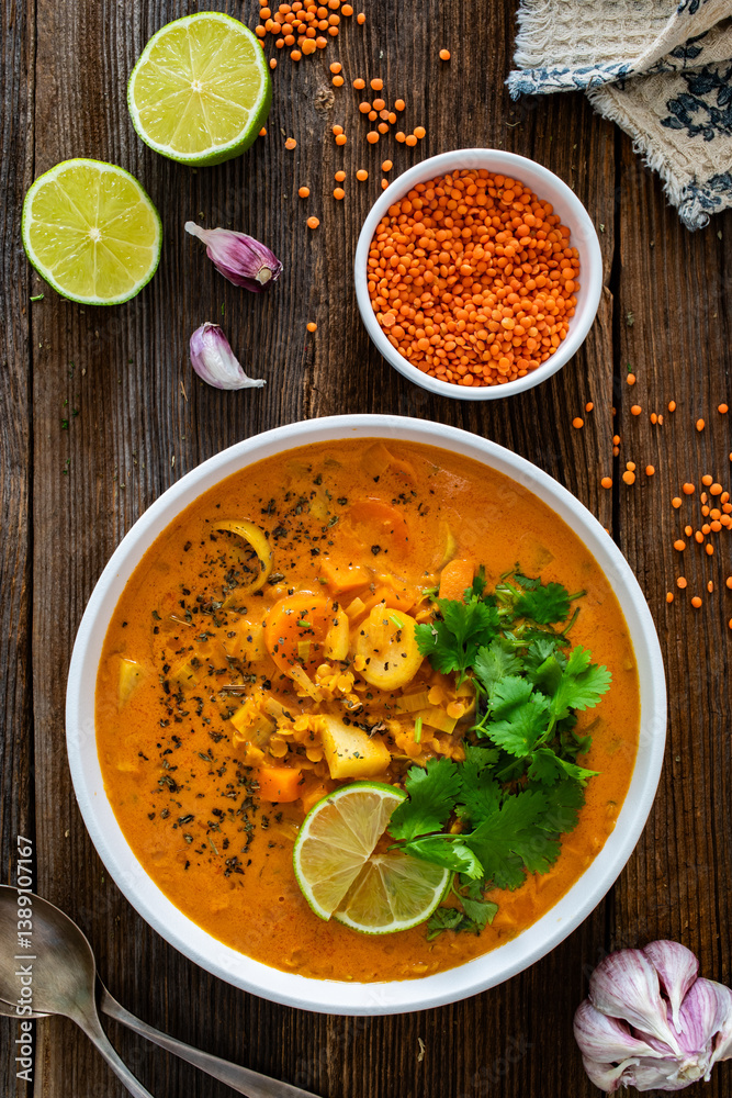 Red lentil sweet potato and coconut soup on wooden table