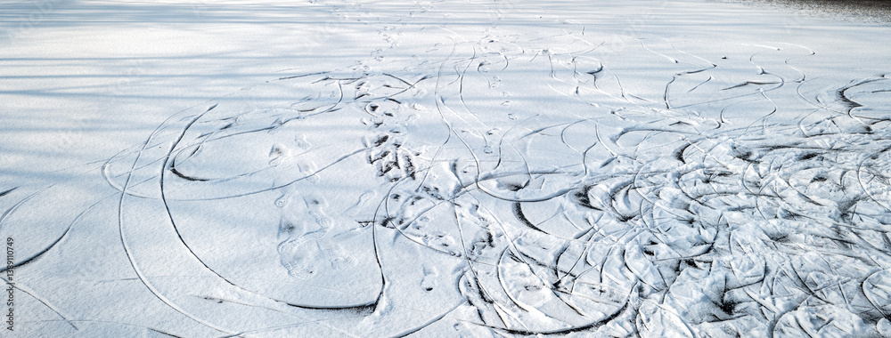 Frozen lake covered in snow. Skate tracks in the snow.