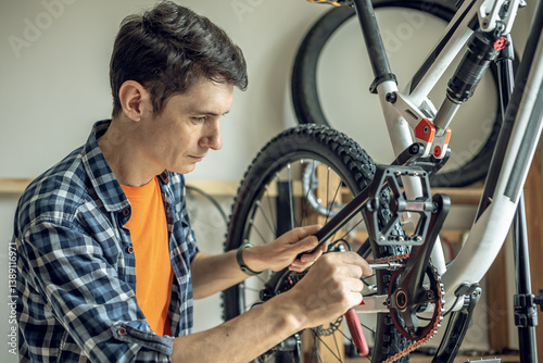 Man is performing maintenance on his mountain bike. Concept of fixing and preparing the bicycle for the new season