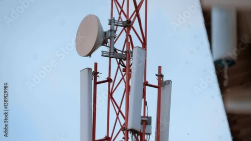 Telecommunication tower with 3g, 4g and 5g antennas installed is standing against the cloudy rainy sky