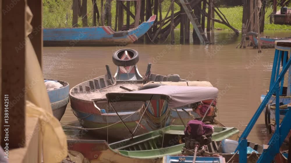 Traditional Cambodian low profile fisherman wooden boats stand on a leash in the river