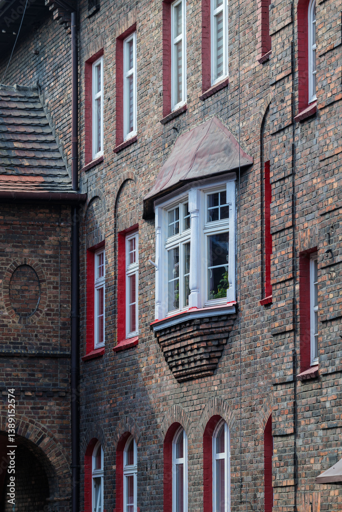 Brick facade of a tenement house in a workers' housing estate. Beautiful window detail. White window frames. Bay window. Historic housing estate Katowice Nikiszowiec. Poland