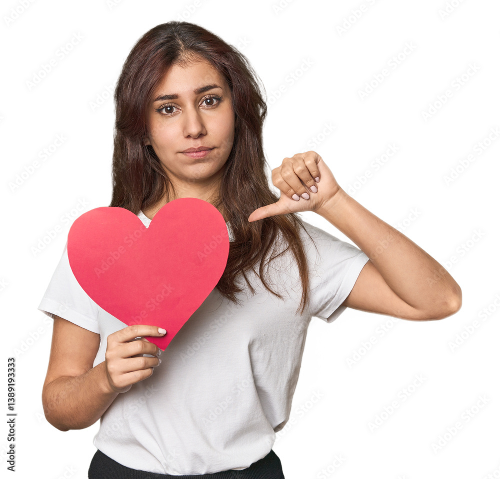 Middle Eastern woman holding paper heart showing a dislike gesture, thumbs down. Disagreement concept. Middle Eastern woman holding paper heart showing a dislike gesture, thumbs down. Disagreement concept.