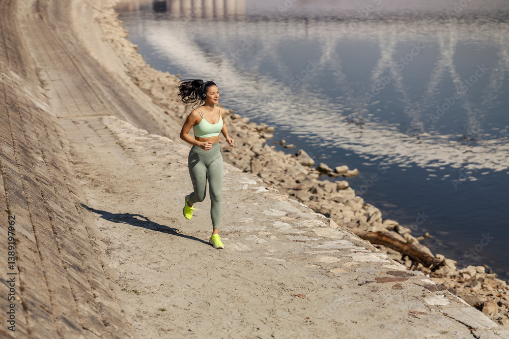 Full length of fit active sportswoman running near river.