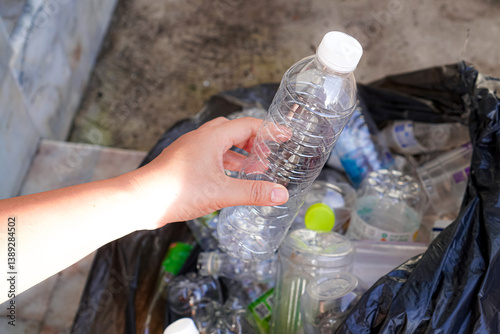 Image of used plastic water bottles being placed in black plastic garbage bags to properly separate waste according to the concept of sustainability at home.