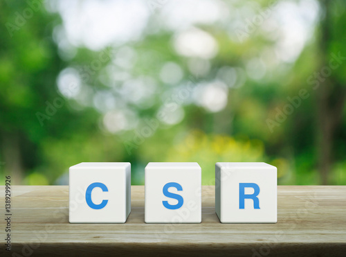 CSR acronym on white block cubes on wooden table over blur green tree in park, Corporate Social Responsibility concept