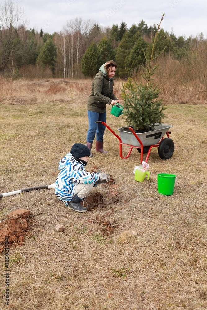 Families enjoy a winter day planting a tree in an open field surrounded by nature