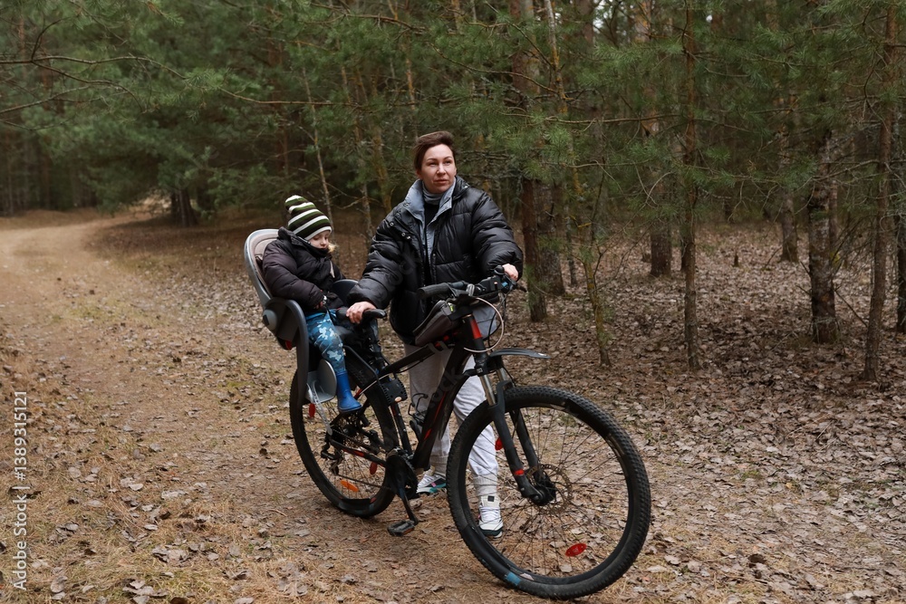 Father biking with child in a forest, enjoying a peaceful afternoon in nature during autumn