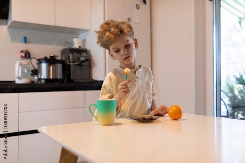 Child engaging in playful activity with colorful items in a bright kitchen during morning hours