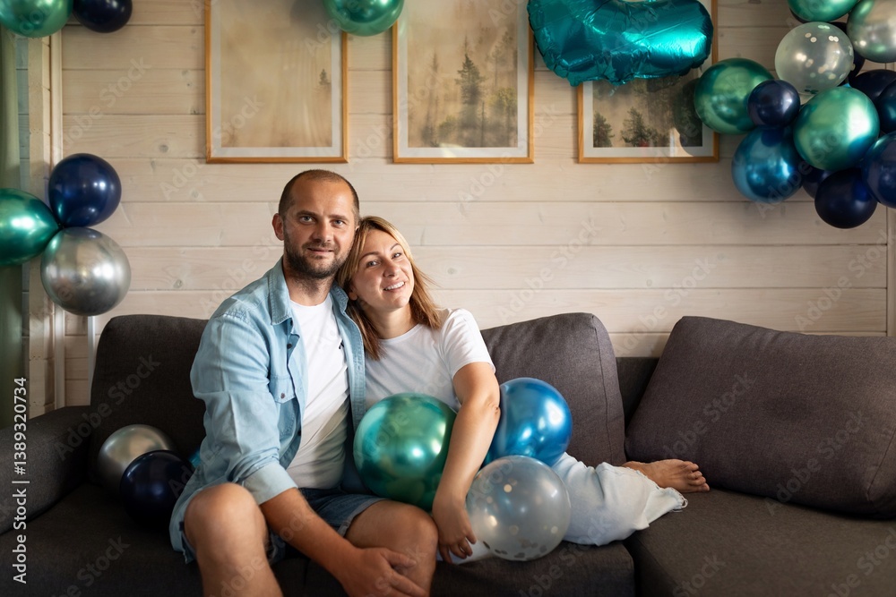Couple celebrating special occasion with blue and green balloons in cozy indoor setting