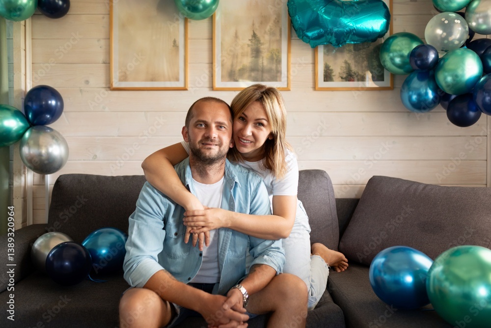 Couple celebrates special occasion in cozy indoor setting with colorful balloons and decorative accents