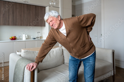 Canvas Print Lonely retiree with backache leans on sofa for support due to severe lumbar pain