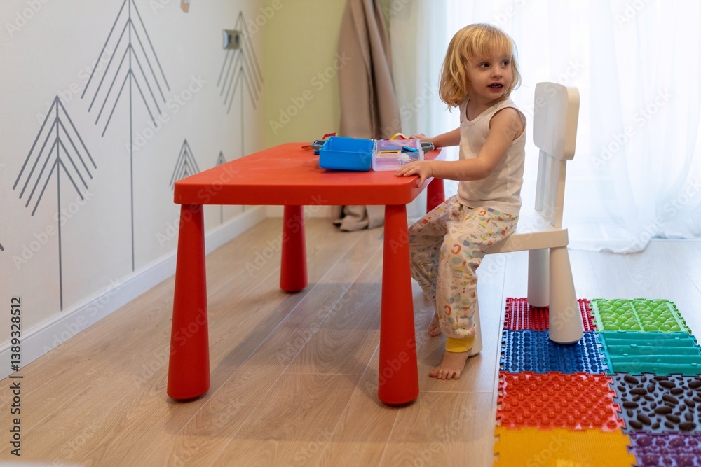 Young child plays at a colorful table in a bright, cheerful playroom filled with toys and soft textures during the daytime