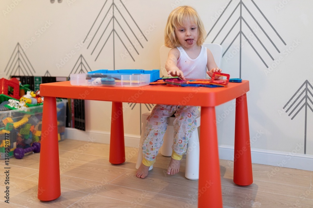 Child engages in creative play at a colorful table inside a bright room during the day