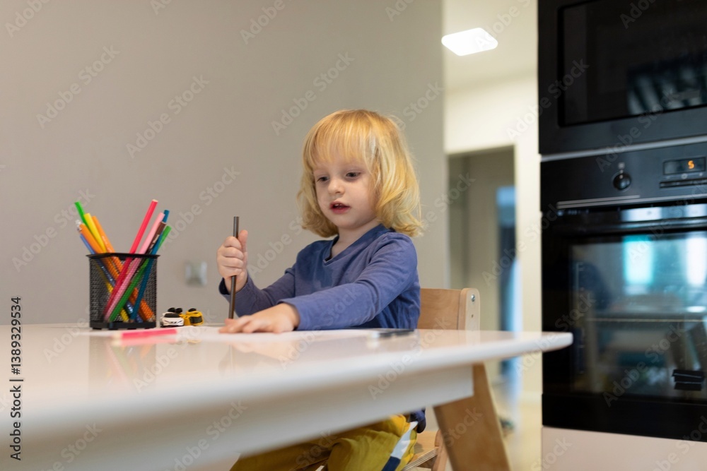 Child engaged in creative drawing at home with colorful supplies on a bright kitchen table