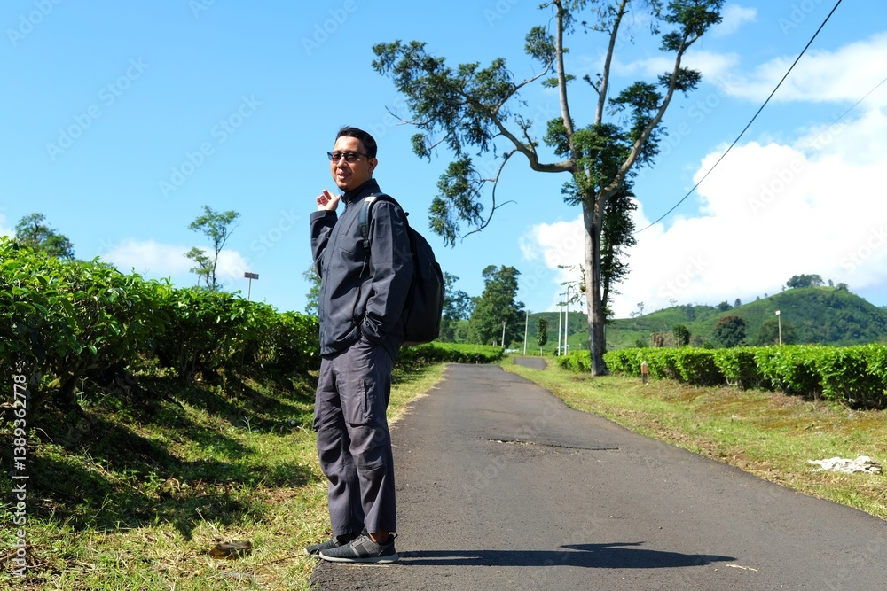 A solo traveler walks down a rural path between lush tea plantations under clear blue skies, enjoying peaceful nature and the freedom of solo exploration in the countryside. A solo traveler walks down a rural path between lush tea plantations under clear blue skies, enjoying peaceful nature and the freedom of solo exploration in the countryside.