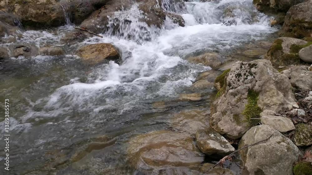 A raging mountain river in close-up. The purest water flows down the stones in a strong stream. The river flows rapidly from the winter melting of snow. The concept of nature ecology, water resources A raging mountain river in close-up. The purest water flows down the stones in a strong stream. The river flows rapidly from the winter melting of snow. The concept of nature ecology, water resources