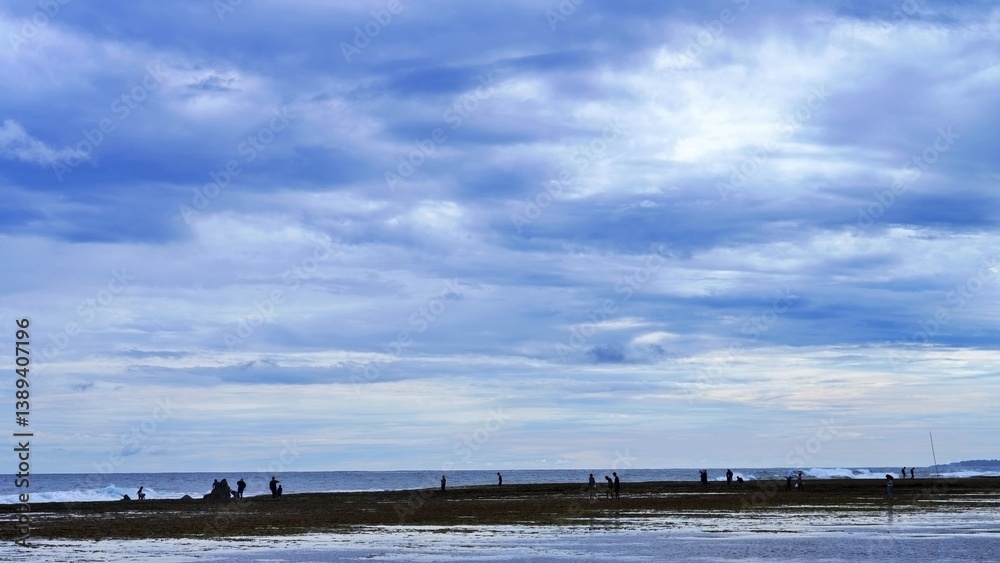 Cloudy sky over a beach with people. Coastal landscape. Cloudy sky over a beach with people. Coastal landscape.