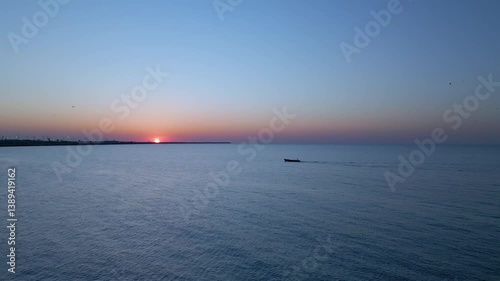 Small fishing boat slowly sailing back at sunrise