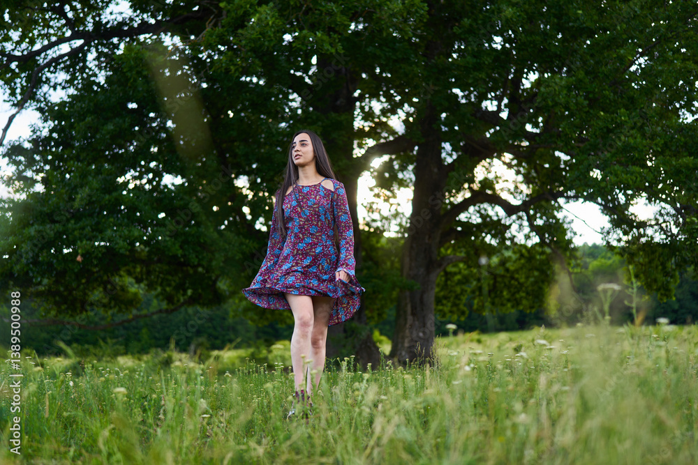 Woman in floral dress standing in summer meadow.........