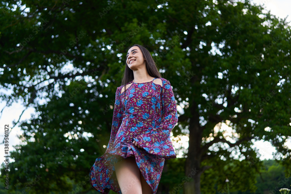 Smiling woman in floral dress walking through a meadow.........