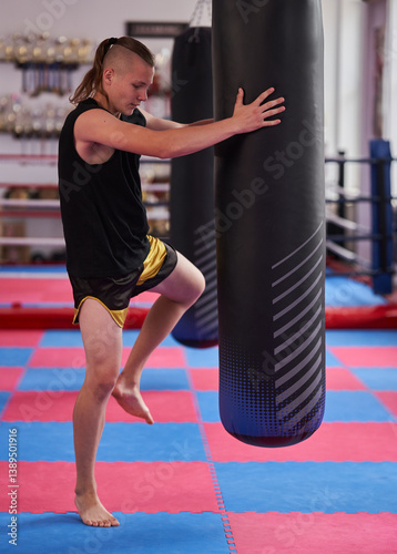 Obraz na płótnie Teenager practicing knee strike into heavy bag in martial arts gym......... w salonie