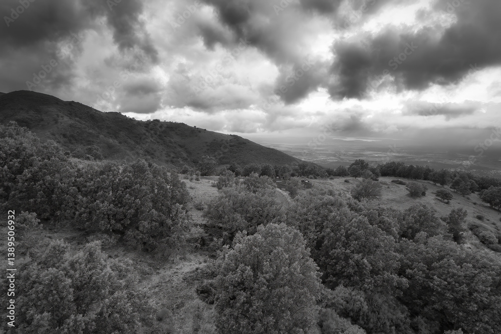 Moody mountain landscape with dramatic clouds in black and white.