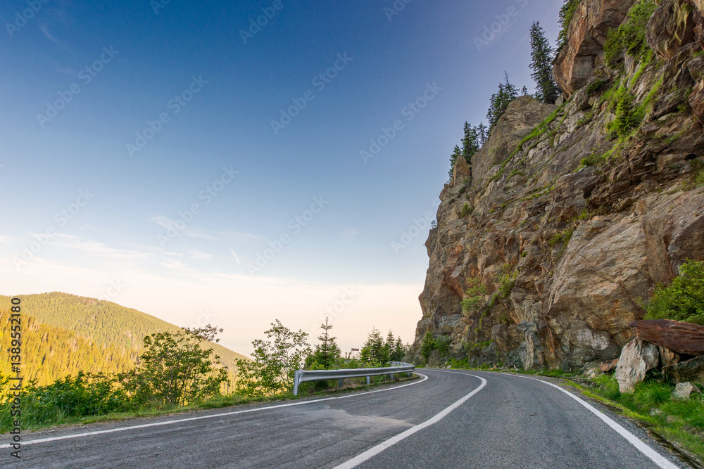 transfagarasan road curve near steep rocky slope. great outdoors of fagaras mountain ridge of romania in summer. dangerous alpine pass in carpathians. popular travel destination of europe