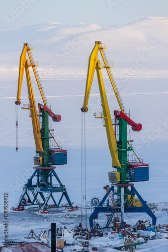 Obraz na płótnie Cargo seaport in the Arctic. Large harbor cranes on a background of ice and snow. Winter industrial landscape. Industry and transport infrastructure in the Far North. Anadyr sea port, Chukotka, Russia w salonie
