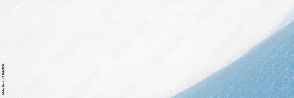 Wide panoramic winter background with snowy ground. Natural snow texture. Wind sculpted patterns on snow surface. Closeup top view with copy space.