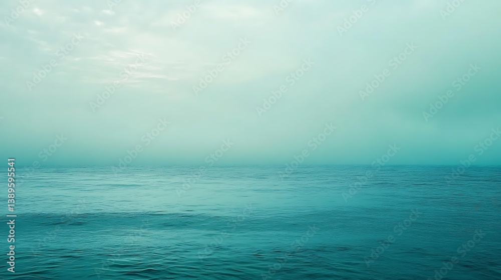 Fototapeta premium Calm teal ocean under a hazy sky.