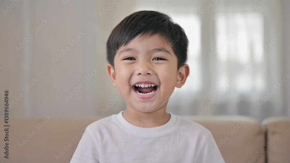 A young boy sitting on a couch, smiling and laughing