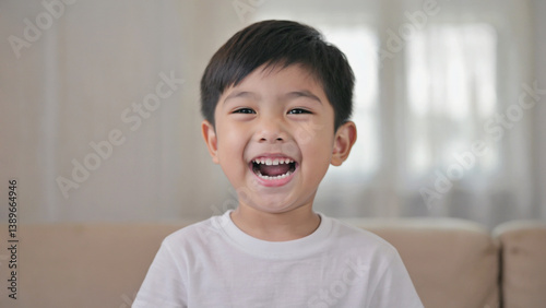 Obraz na płótnie A young boy sitting on a couch, smiling and laughing w salonie