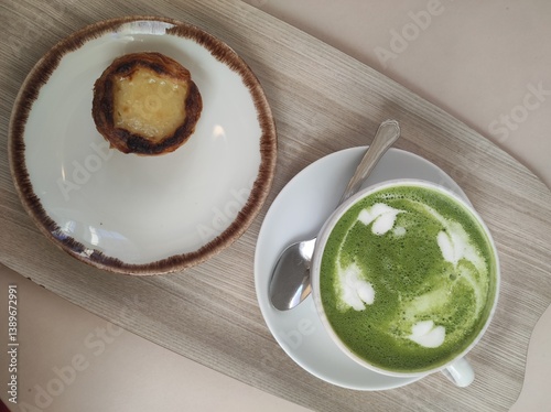 A cup of matcha latte green tea and cake on wooden table