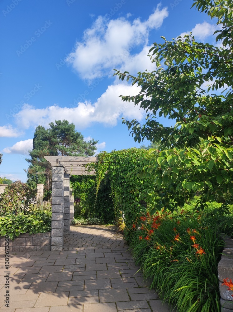 garden with stone arch, blue sky and white clouds in background