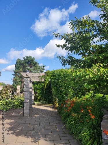 Obraz na płótnie garden with stone arch, blue sky and white clouds in background w salonie
