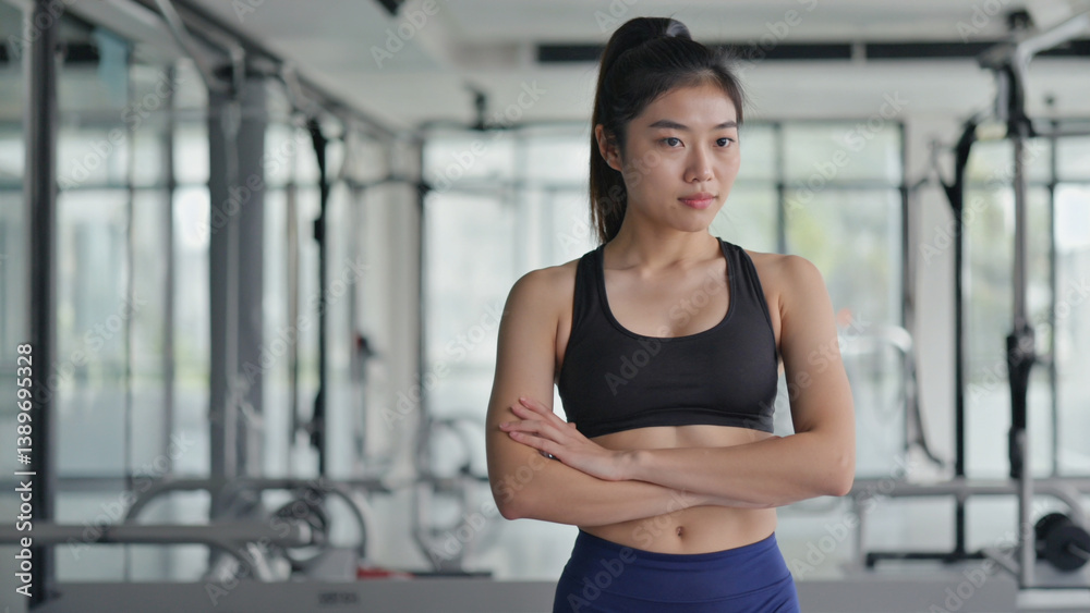 A person standing in a fitness center, arms crossed, possibly waiting or contemplating