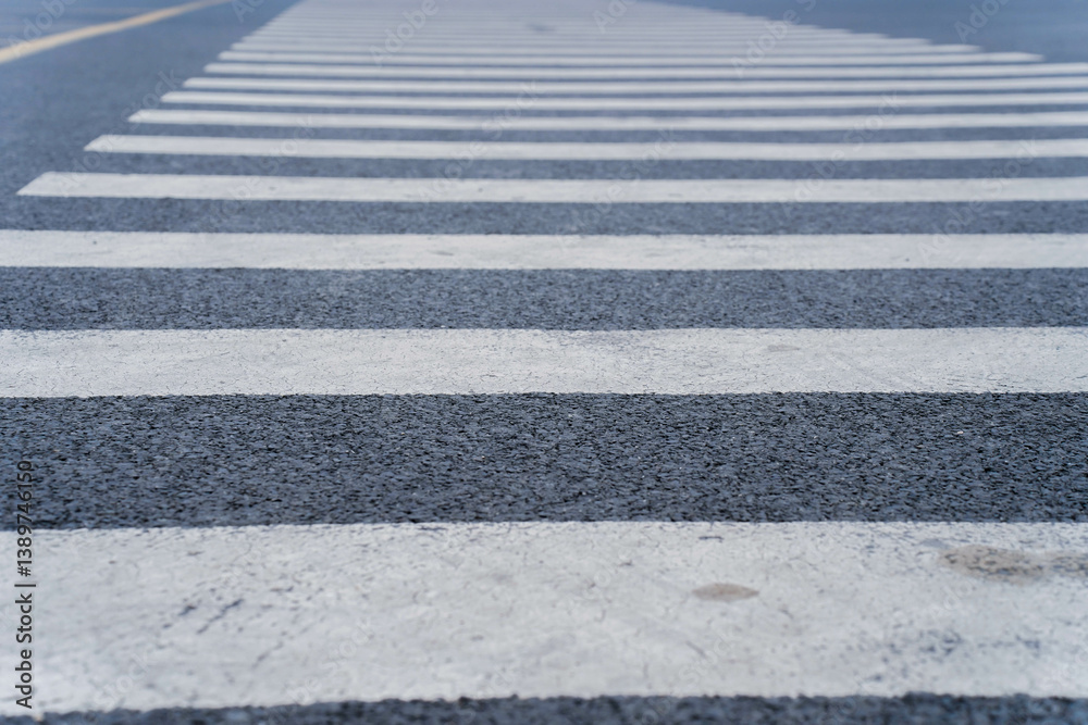 Empty crosswalk on a city street with striped white lines, indicating pedestrian crossing area. Concept of urban infrastructure, pedestrian safety, and road design. High quality photo