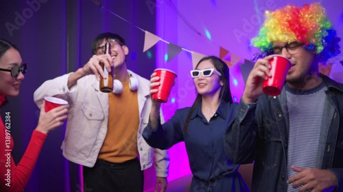 Happy asian diverse group friends say hi to the camera on party with neon light. Home party friends having fun, singing and dancing together. Smiling men and women enjoying time together indoor.