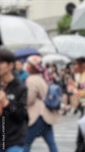 東京都市風景　イメージ　雨の日に傘を刺して歩く人々　ぼかし
