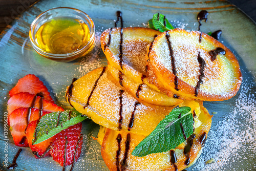 Obraz na płótnie sweet pancakes with syrup, powdered sugar, honey and strawberries served on a blue plate w salonie