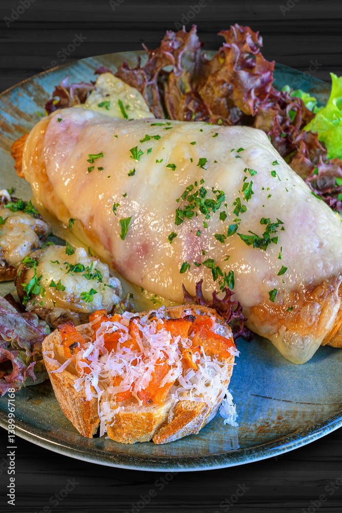 croisant topped with ham and cheese, toasted white bread with tomato and parmesan cheese