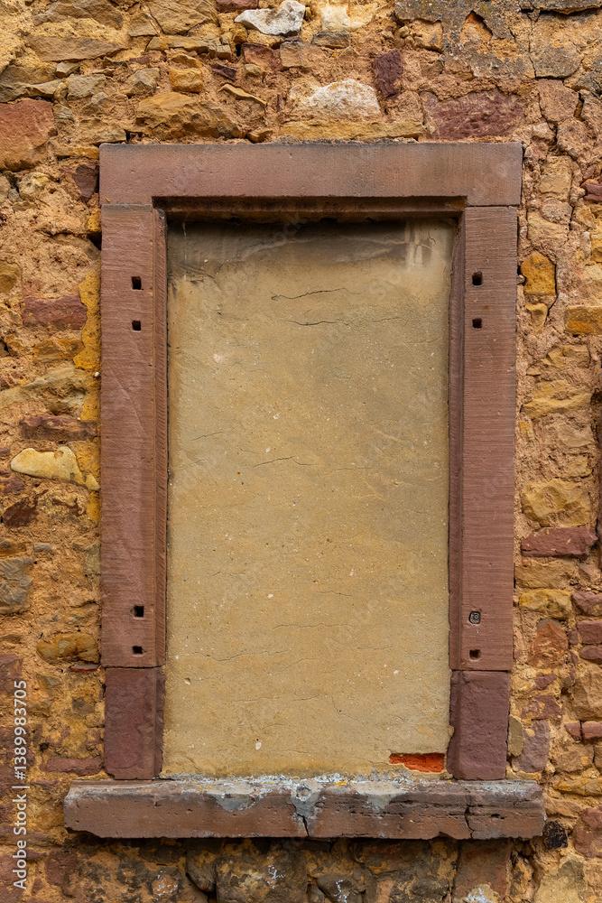 Old stone wall with a blank window frame in a rustic building showing signs of wear in sunny weather Old stone wall with a blank window frame in a rustic building showing signs of wear in sunny weather