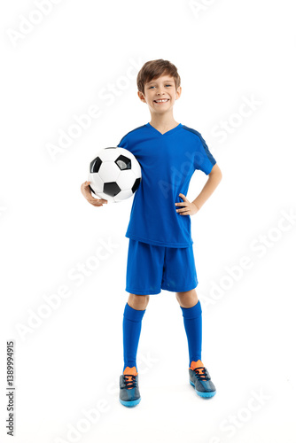 Confident young boy in blue sport outfit posing with classic soccer ball over white background